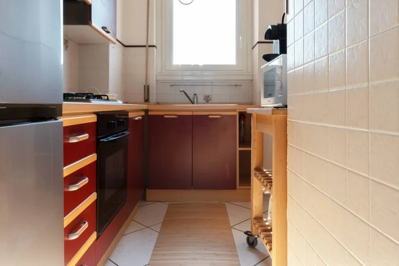 Cucina separata de Il Girasole con ante rosse, piano cottura a gas, forno elettrico e finestra