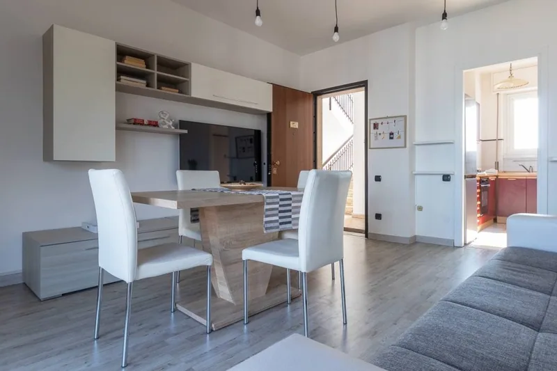 Tavolo da pranzo de Il Girasole con sedie bianche, mobile a giorno e lampadine a sospensione